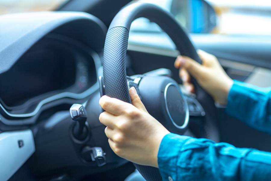 Hände umklammern das Lenkrad eines Autos für sicheres Fahren